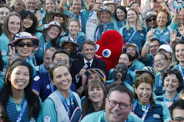 Le président français Emmanuel Macron pose avec des bénévoles alors qu'il visite les compétitions de tir à l'arc pendant les Jeux olympiques de Paris 2024 sur l'Esplanade des Invalides à Paris, le 2 août 2024.