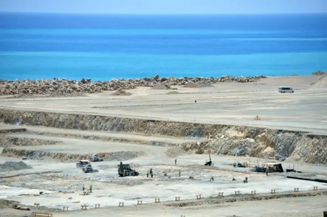 نمایی دور از محل احداث نیروگاه در کنار دریا، کارگران در حال پی‌ریزی فونداسیون