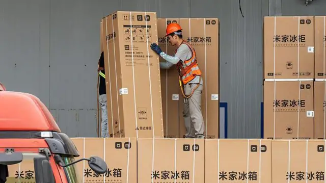 Un trabajador mueve una gran caja que contiene un refrigerador en una bodega en Zhaoqing, provincia de Guangdong, China