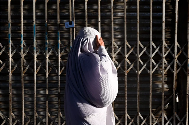 ਬੁਰਕਾ ਪੋਸ਼ ਅਫ਼ਗਾਨ ਔਰਤ ਕੰਧਾਰ ਦੀ ਇੱਕ ਬੰਦ ਦੁਕਾਨ ਦੇ ਗੇਟ ਅੱਗੋਂ ਗੁਜ਼ਰਦੇ ਹੋੇਏ