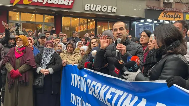 Halep'teki çatışmalara karşı Diyarbakır'da düzenlenen yürüyüşte, pankartın arkasında basın açıklaması yapılıyor.