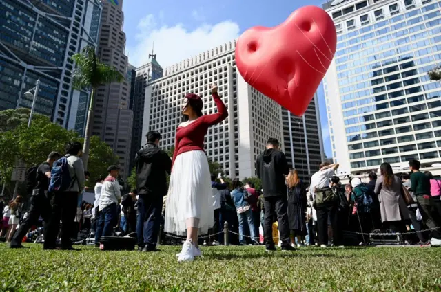 2024年2月14日情人節，香港一名女子手持著巨型的紅心裝置「Chubby Hearts」。