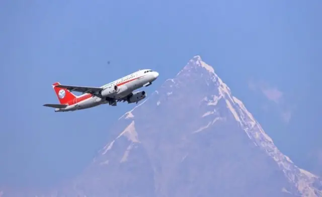 पोखराको आकाशमा उडिरहेको एउटा चिनियाँ विमान। पृष्ठभूमिमा माछापुच्छ्रे हिमाल।