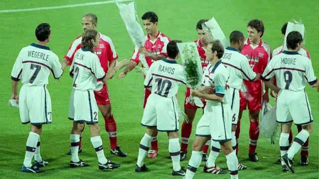 Jogadores dos Estados Unidos recebem flores da Seleção Iraniana antes da partida da 1ª rodada da Copa do Mundo entre EUA (1) e Irã (2) no Stade de Garland em 21 de junho de 1998 em Lyon, França.
