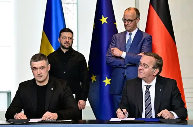 Міністр оборони України Михайло Федоров (ліворуч) і міністр оборони Німеччини Борис Пісторіус (праворуч) підписують документи про співпрацю в присутності канцлера Німеччини Фрідріха Мерца (другий праворуч) і президента України Володимира Зеленського (другий ліворуч) в Берліні 14 квітня 2026 року