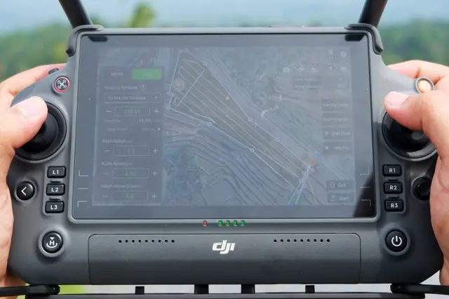 Pilot drone mengendalikan pesawatnya saat pemupukan di sawah. 