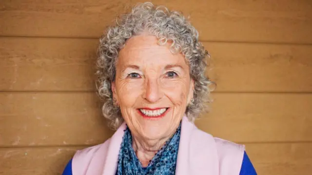 Yaşlı bir kadın kameraya bakıp tebessüm ediyor