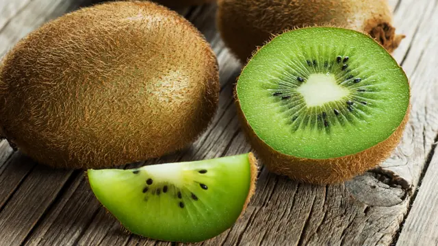 Egész és szeletelt kivik egy fa asztalon, közeli felvételen.