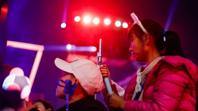 A lady holding phone wit anoda man for front