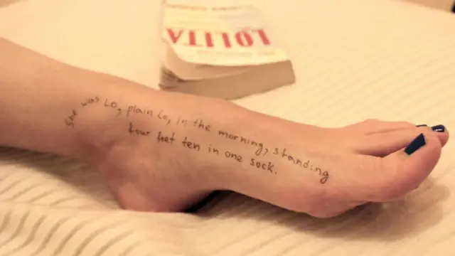 تصویر پای یک زن جوان که نقل قولی از رمان لولیتا، اثر ولادیمیر ناباکوف، بر آن با جوهر سیاه نوشته شده است