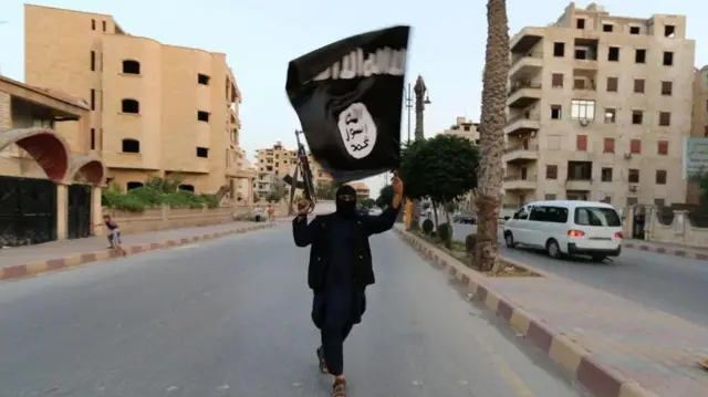 Mwanachama mwenye silaha wa IS anatembea katika mitaa ya Raqqa, Juni 2104