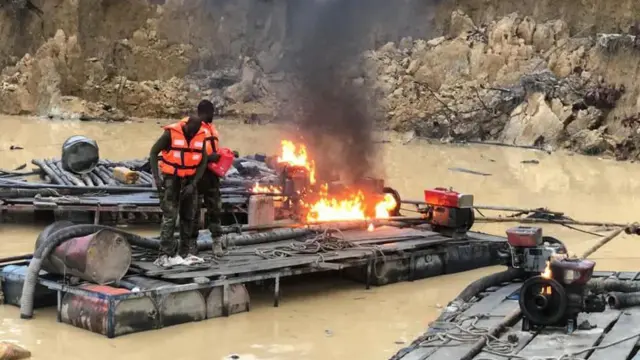 A photo of an illegal mining site with security taskforce burning seized equipment