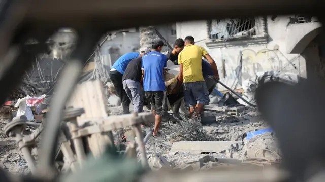 فلسطينيون يبحثون بين أنقاض منازلهم المدمرة عن أي ممتلكات يمكن استخدامها بعد غارة جوية إسرائيلية استهدفت عدة منازل في مخيم جديد شمال غرب النصيرات بقطاع غزة في 29 يوليو/تموز 2025. دُمرت عدة منازل بالكامل في الهجوم، الذي أسفر عن مقتل العديد من الفلسطينيين
