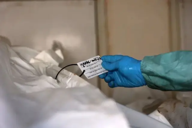 ایک اہلکار ایک فلسطینی کی باقیات کی شناخت کرتے ہوئے اس کے شناختی کارڈ کی جانچ کر رہا ہے