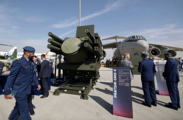 مردم در مقابل یک هواپیمای جنگی و یک جنگ افزار دیده میشوند