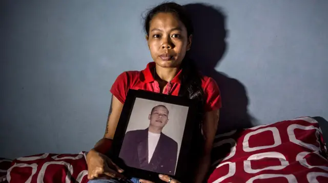 ኢንዶኔዥያ ውስጥ የባሏን ፎቶ የያዘች ሴት