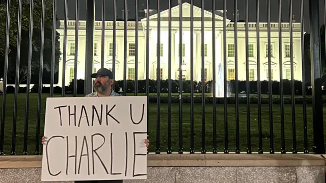 Un hombre sujeta un cartel que dice "Gracias, Charlie", en inglés, frente a la Casa Blanca
