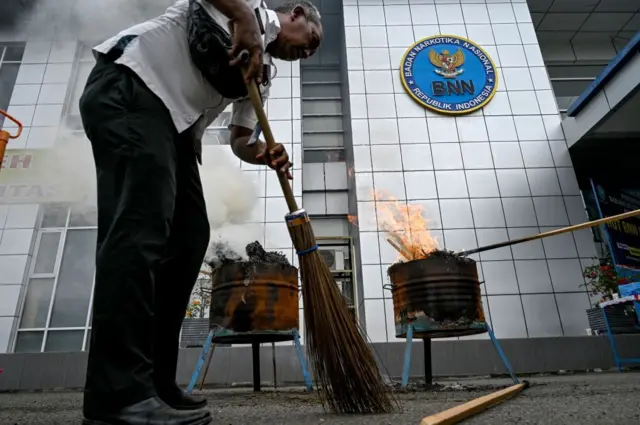 Seorang petugas BNN membersihkan hasil pembakaran ganja sitaan di Banda Aceh pada 24 Maret 2022.