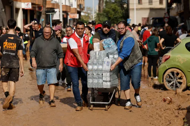 Voluntários levam garrafas d'águapoker jogo de azarcarrinhopoker jogo de azarsupermercado; eles caminham sobre rua repletapoker jogo de azarlama