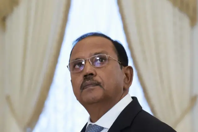 ভারতের জাতীয় সুরক্ষা উপদেষ্টা অজিত ডোভাল চশমা পরে ওপরের দিকে তাকিয়ে আছেন। পেছনে হালকা ঘিয়ে রংয়ের পর্দা দুই পাশে ভাঁজ করা।