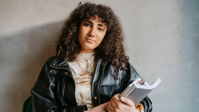 طالبة جامعية تمسك دفاتر وكتب