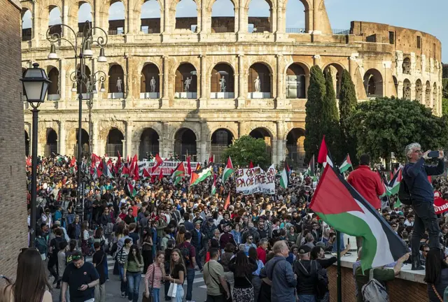 ellerinde filistin bayrakları olan yüzlerce kişi roma'daki kolezyum binasının önünden yürüyor. 
