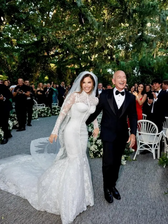 Lauren Sánchez wear Dolce & Gabbana haute couture gown while Jeff Bezos place im arm around her while e wear one smart black tuxedo