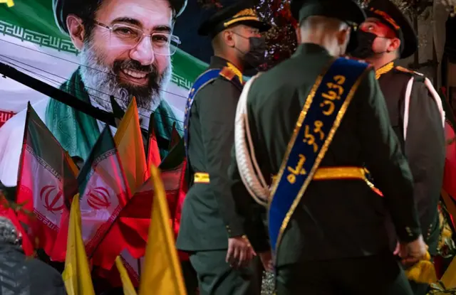 Deux soldats iran debouts près d'une affiche de Mojtaba Khamenei