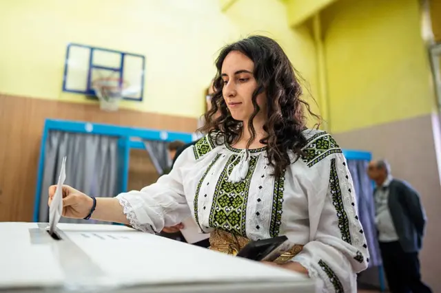Женщина в национальной одежде голосует на выборах в Румынии