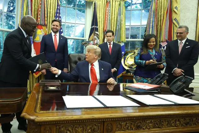 سلم الرئيس الأمريكي دونالد ترامب قلماً لوزير الخارجية والتعاون الرواندي، أوليفييه ندوهونغيريهي، خلال لقائه به ووزيرة خارجية جمهورية الكونغو الديمقراطية، تيريز كاييكوامبا فاغنر، في المكتب البيضاوي بالبيت الأبيض في ٢٧ يونيو/حزيران ٢٠٢٥