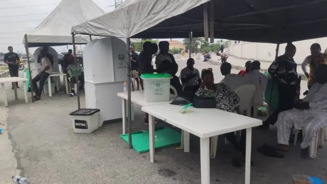 Àwọn òṣìṣẹ́ INEC tó ń dúró de àwọn ènìyàn VGC níta láti wá dìbò 