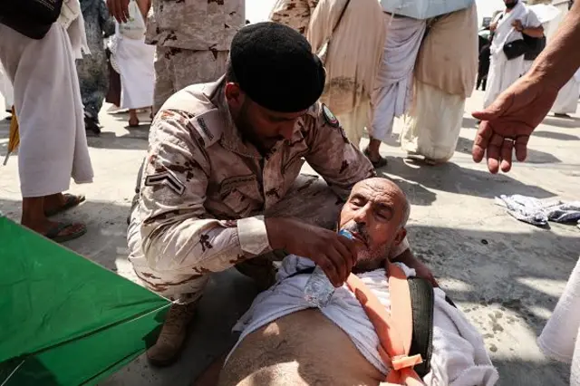 A security guard helping a sick pilgrim.