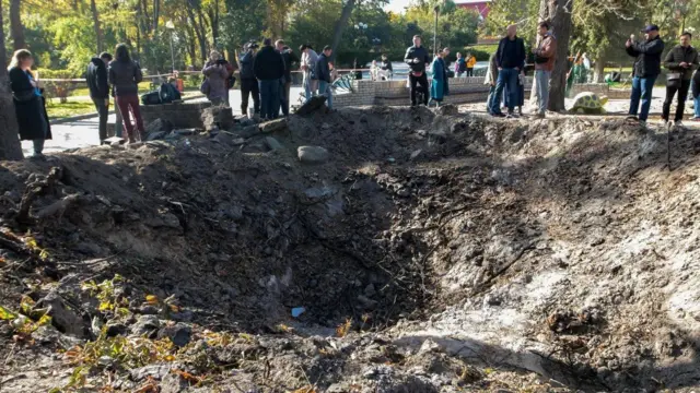 Величезна вирва в парку Шевченка після ракетного обстрілу Києва, люди стоять навколо неї, їх приблизно 15
