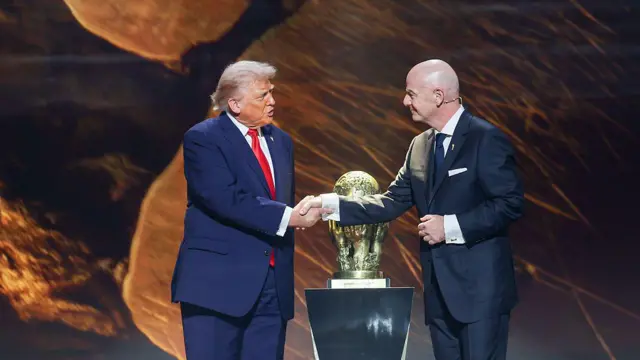 Donald Trump (i) estrecha la mano del presidente de la FIFA, Gianni Infantino, junto a un trofeo.