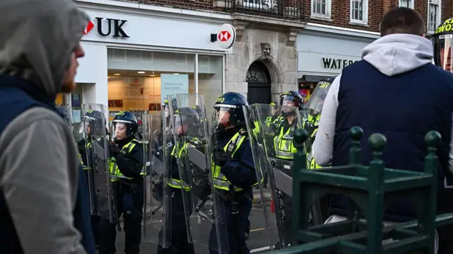 Policja pojawiła się na głównej ulicy w Epsom, gdzie mieszkańcy protestowali po doniesieniach o gwałcie na kobiecie w wieku około 20 lat. Do zdarzenia miało dojść w nocy po wyjściu z klubu, przed kościołem. Policja wszczęła śledztwo, ale nie ujawniła dotąd opisów podejrzanych.