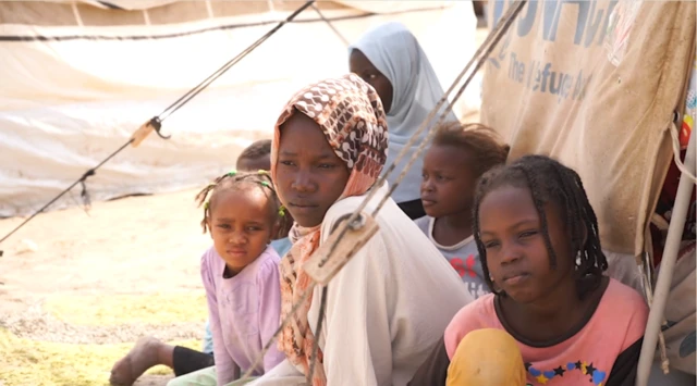 Safaa, une jeune Soudanaise de 14 ans, est photographiée dans un camp de réfugiés avec cinq autres enfants. Safaa porte un vêtement beige à manches longues et un foulard à motifs.
