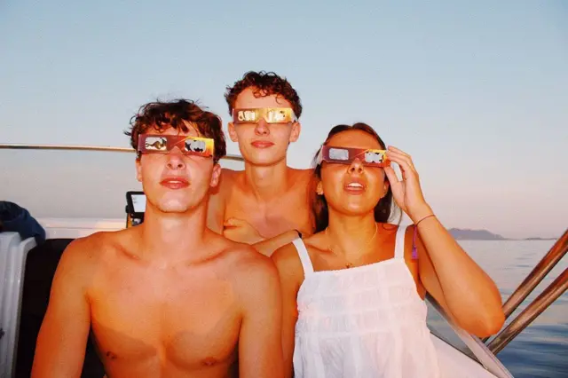 Grupo de jóvenes observando un eclipse solar desde una embarcación en el mar Mediterráneo, frente a Bandol (Provenza-Alpes-Costa Azul, Francia).