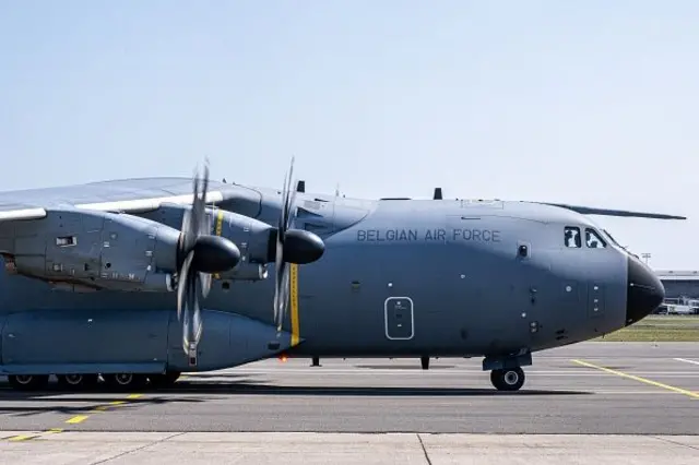Belgian Air Force (Belçika Hava Kuvvetleri) yazılı bir bir uçak pistte duruyor, iki pervanesi döner durumda.