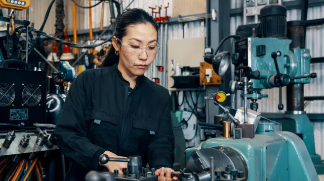 O femeie folosește echipamente de prelucrare într-un atelier de fabricare de metale din Japonia.