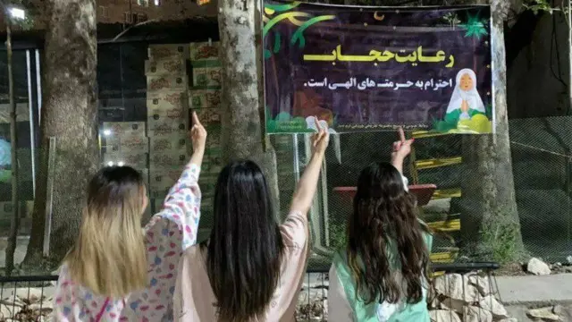 سه زن معترض در برابر یک بنر تبلیغ حجاب