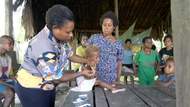 Grace M. Weya, perawat dari Puskesmas Kasonaweja, Kabupaten Mamberamo Raya, sedang memeriksa kesehatan seorang anak bernama Marince di kampung Anggreso. 