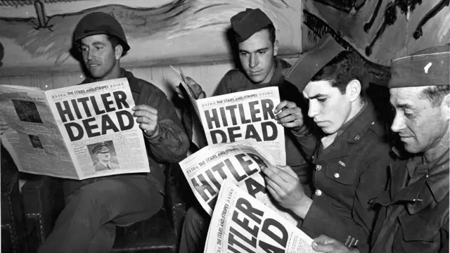 正在法国巴黎中转的美军士兵阅读《星条旗报》号外，头版头条标题为〈希特勒已死〉（2/5/1945）
