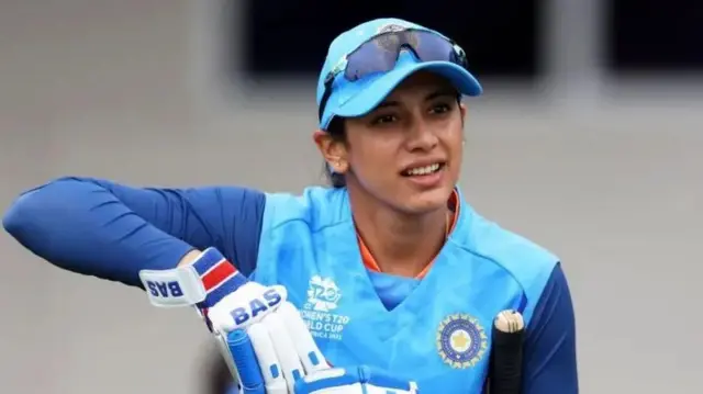 ස්ම්‍රිති මන්දානා ඉන්දීය ක්‍රිකට් ජර්සිය හැද ක්‍රිකට් බැට් එකක් අත තබාගෙන සිටියි.