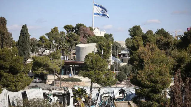 تُظهر الصورةٌ علماً إسرائيلياً يرفرف فوق مبانٍ مُهدمة داخل مقر وكالة الأمم المتحدة لإغاثة وتشغيل اللاجئين الفلسطينيين (الأونروا) في حي الشيخ جراح بالقدس الشرقية المُحتلة.