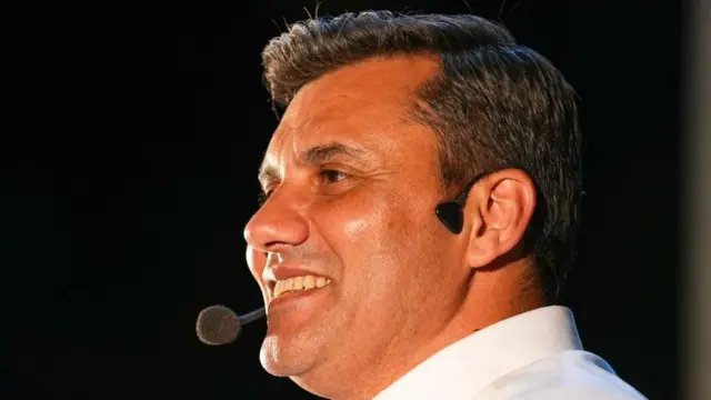 Beyaz gömlek giymiş Ferdi Zeyrek konuşma yaptığı sırada gülümsüyor