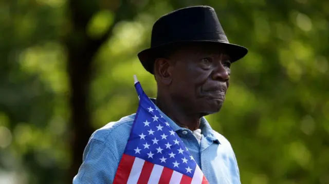 Un hombre haitiano sostiene una bandera estadounidense en Ohio, Estados Unidos.