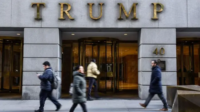 Pessoas caminhandobaixar app f12 betfrente a fachada do Trump Tower 