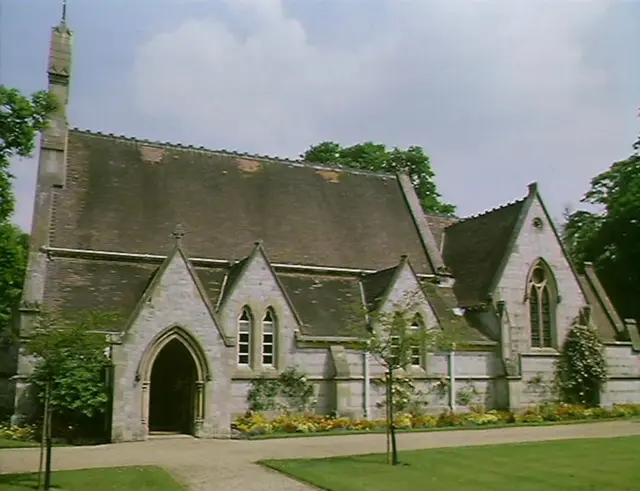 کلیسایی با مناره، سقف شیروانی و ورودی قوسی شکل. مسیری و چمن‌های مرتبی در جلوی آن قرار دارند که درختان کوچکی روی چمن‌ها روییده‌اند