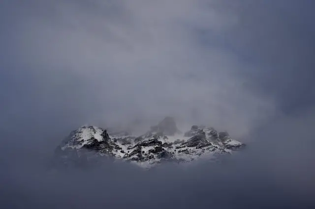La cresta nevada de las montañas en el paso de Stelvio, entre nubes