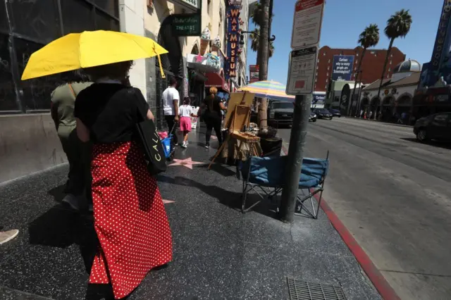 Cristy Gerth, dari Dallas, Texas, menikmati naungan payung saat gelombang panas terjadi di sepanjang Hollywood Blvd di Hollywood pada 3 September 2022.